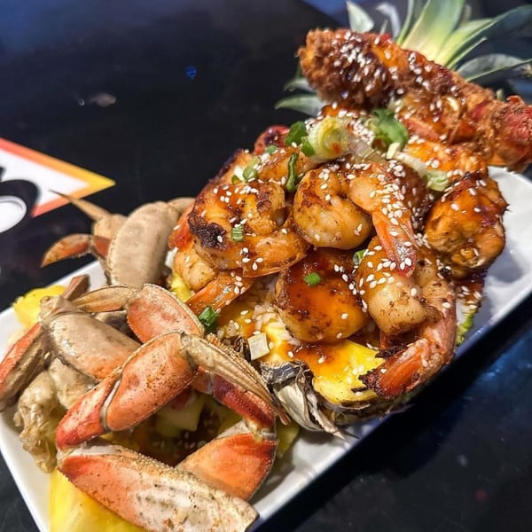 Cali Kitchen and Bar's seafood platter with crab legs, shrimp, and pineapple on a white plate.