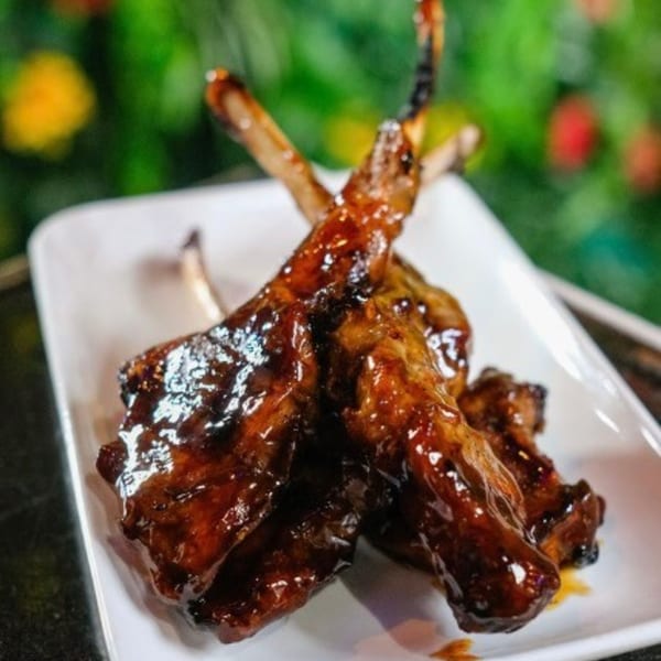 Cali Kitchen and Bar's glazed ribs, glistening with sauce, on a white rectangular plate.