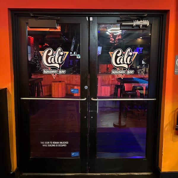 Double glass doors of Cali Kitchen + Bar, with the restaurant logo on each door.
